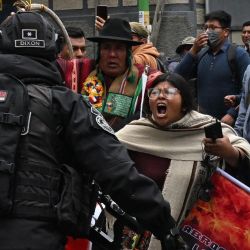 Una mujer grita consignas frente a agentes de la policía antidisturbios durante una protesta para exigir al gobierno del presidente boliviano Luis Arce una solución a la falta de dólares y el desabastecimiento de combustible en La Paz. | Foto:AIZAR RALDES / AFP