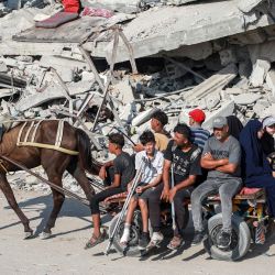 En Khan Yunis, en el sur de la Franja de Gaza, varias personas viajan en un carro tirado por caballos entre los escombros de un edificio derrumbado, en medio de la guerra en curso en el territorio palestino entre Israel y Hamás. | Foto:Bashar Taleb / AFP