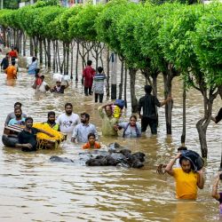 La gente lleva sus pertenencias mientras camina por una calle inundada tras las fuertes lluvias monzónicas, en Vijayawada. Las intensas lluvias monzónicas y las inundaciones en los estados del sur de la India han matado al menos a 25 personas, y miles han sido rescatadas y trasladadas a campamentos de socorro, dijeron los funcionarios de desastres. | Foto:CHANDU LUMBURU / AFP