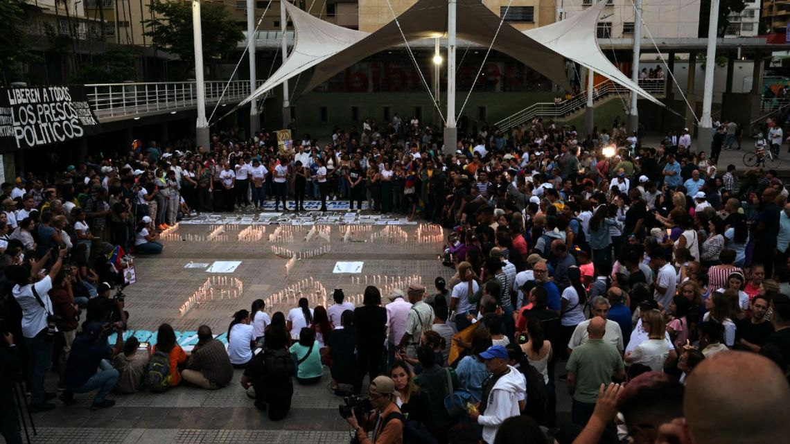 People surround lit candles forming the words 'Freedom and Peace' during a vigil called by the opposition demanding freedom for political prisoners arrested during protest following the contested re-election of Venezuelan President Nicolás Maduro in Caracas, August 8, 2024. 