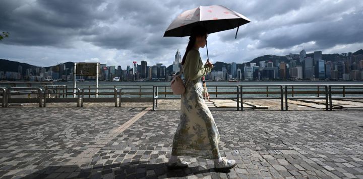 Los turistas caminan por el paseo marítimo del puerto Victoria en Hong Kong.