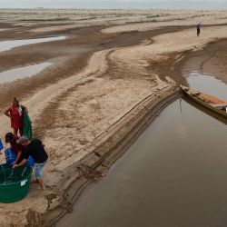 Hombres recogen agua potable junto a un banco de arena del río Madeira en la comunidad de Paraizinho, en Humaita, estado de Amazonas, norte de Brasil. Más de mil localidades brasileñas están en alerta por los bajos niveles de humedad, comparables en algunos casos a desiertos como el Sahara, mientras el país enfrenta la peor sequía de su historia y los incendios no cesan. | Foto:MICHAEL DANTAS / AFP