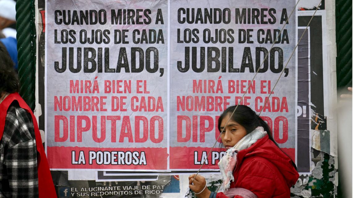 A woman walks past posters against the veto by President Javier Milei of a law to increase pensions in Buenos Aires on September 11, 2024. 