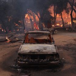 Un vehículo quemado se ve cerca de una estructura en llamas en El Cariso Village durante el incendio del aeropuerto cerca de Lake Elsinore, California. Los incendios forestales fuera de control que rodean Los Ángeles continuaron creciendo, obligando a las familias a evacuar y cubriendo el cielo con humo asfixiante. El incendio del aeropuerto en el condado de Orange, que avanza rápidamente, ha consumido más de 9.000 acres (3.600 hectáreas) desde que se inició accidentalmente por trabajadores que operaban equipo pesado. | Foto:DAVID SWANSON / AFP
