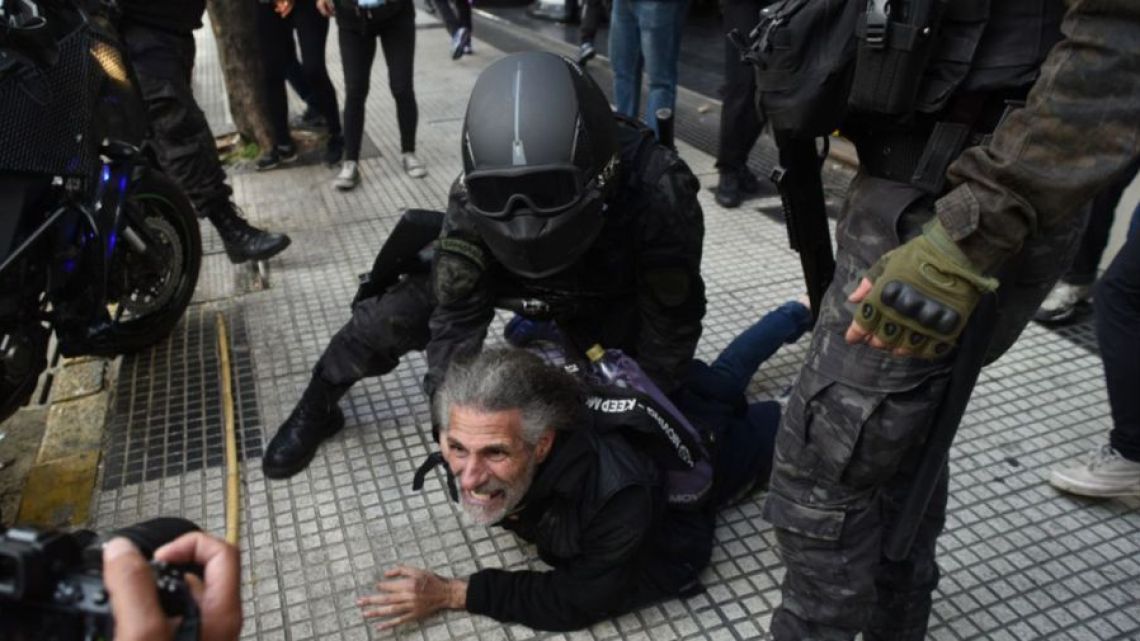 A demonstrator is pinned to the ground by a security officer during a demonstration outside Congress on September 11, 2024.