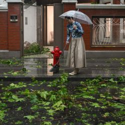 Una mujer barre ramas y hojas de árboles fuera de una tienda derribada por el paso del tifón Bebinca en Shanghái. | Foto:HECTOR RETAMAL / AFP