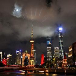 La luna llena se eleva sobre los rascacielos del distrito financiero de Lujiazui en Shanghái, China. | Foto:Hector Retamal / AFP