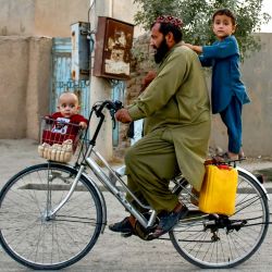 Un hombre afgano con niños anda en bicicleta por una calle de la aldea de Rabat, en el distrito de Sholgara, provincia de Balkh. | Foto:Atif Aryan / AFP