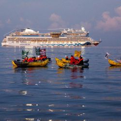 Activistas de las ONG Stop croisieres y Extinction Rebellion France sostienen pancartas mientras bloquean el crucero AIDAstella en la entrada norte del puerto de Marsella en kayaks, en Marsella, sur de Francia, para protestar contra los cruceros y sus impactos ambientales y contaminaciones. | Foto:CLEMENT MAHOUDEAU / AFP