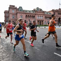 Los corredores compiten mientras pasan por el palacio presidencial Casa Rosada durante el Maratón Internacional de Buenos Aires en Buenos Aires. | Foto:LUIS ROBAYO / AFP