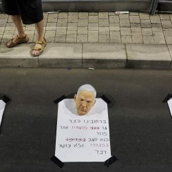 Un manifestante se encuentra detrás de máscaras del primer ministro israelí, Benjamin Netanyahu, colocadas en carteles durante una protesta antigubernamental que pide acciones para asegurar la liberación de los rehenes israelíes cautivos desde los ataques del 7 de octubre por militantes palestinos en la Franja de Gaza, frente al Ministerio de Defensa israelí en Tel Aviv, en medio de la guerra en curso entre Israel y el grupo militante Hamás. | Foto:JACK GUEZ / AFP