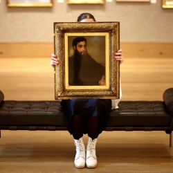 Un empleado de una casa de subastas sostiene un cuadro titulado "Retrato de Lucas Alexander Ionides" del artista estadounidense James McNeill Whistler durante una presentación preliminar para la prensa en la casa de subastas Bonhams en Londres. | Foto:HENRY NICHOLLS / AFP