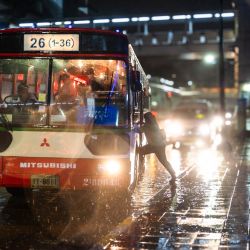 Una mujer sube a un autobús durante una fuerte lluvia en Bangkok, Tailandia. | Foto:Chanakarn Laosarakham / AFP