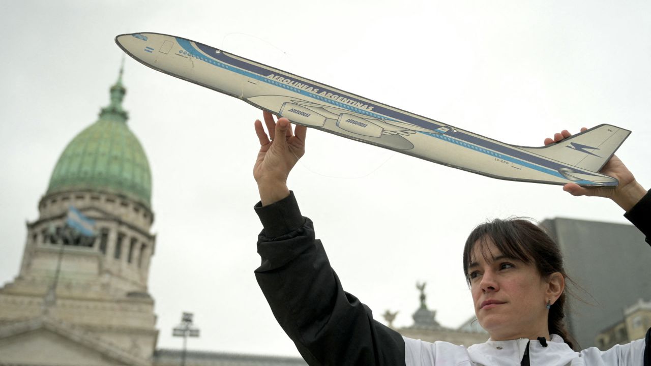 Un miembro de los sindicatos aeronáuticos sostiene un avión de cartón para protestar contra la privatización de la aerolínea estatal Aerolíneas Argentinas frente al Congreso en Buenos Aires. El gobierno del presidente ultraliberal argentino Javier Milei, en medio de un tira y afloja con los sindicatos de la aviación, ha dado un paso más hacia la desregulación al anunciar que los vuelos nacionales estarán abiertos a partir de ahora a aeronaves y tripulaciones extranjeras. | Foto:JUAN MABROMATA / AFP