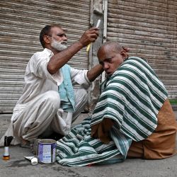 Un barbero atiende a un cliente en un mercado de Lahore. Pakistán dijo que tendría que pasar por un "dolor transitorio" después de que el Fondo Monetario Internacional acordara un nuevo paquete de ayuda de 7.000 millones de dólares para apuntalar su tambaleante economía. | Foto:Arif Ali / AFP