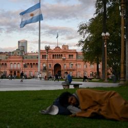 Un hombre sin hogar duerme en la Plaza de Mayo frente a la Casa Rosada, el palacio presidencial de Buenos Aires. La pobreza en Argentina alcanzó al 52,9 por ciento de la población en los primeros seis meses del gobierno de Javier Milei, lo que refleja el impacto de la devaluación del 50 por ciento realizada en diciembre y una política de ajuste fiscal que, centrada en la reducción del gasto y la inflación, profundizó la recesión económica. | Foto:LUIS ROBAYO / AFP