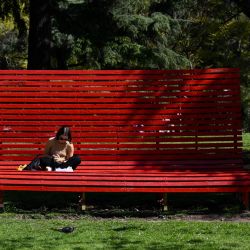 Una mujer come sentada en una silla gigante en el Parque Las Heras de Buenos Aires. | Foto:LUIS ROBAYO / AFP)