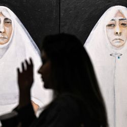 Una visitante pasa junto a las obras de arte expuestas en la exposición "Mujeres en la guerra - Palestina" en la Plataforma de Arte Contemporáneo (CAP) en la ciudad de Kuwait. La exposición presenta las obras de arte de más de 100 artistas de todo el mundo que han donado generosamente su arte en apoyo de Palestina y como un llamado unificado a la paz en el mundo árabe. | Foto:Yasser Al-Zayyat / AFP