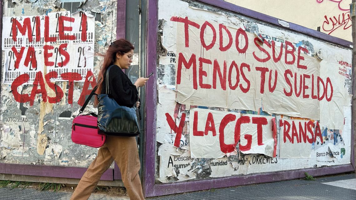 A woman walks past graffiti slamming President Javier Milei and unions in Buenos Aires on September 25, 2024.