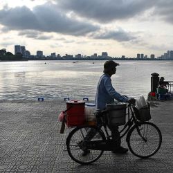 Un vendedor ambulante camina con su bicicleta junto al lago Oeste en Hanoi. Foto de NHAC NGUYEN / AFP | Foto:AFP