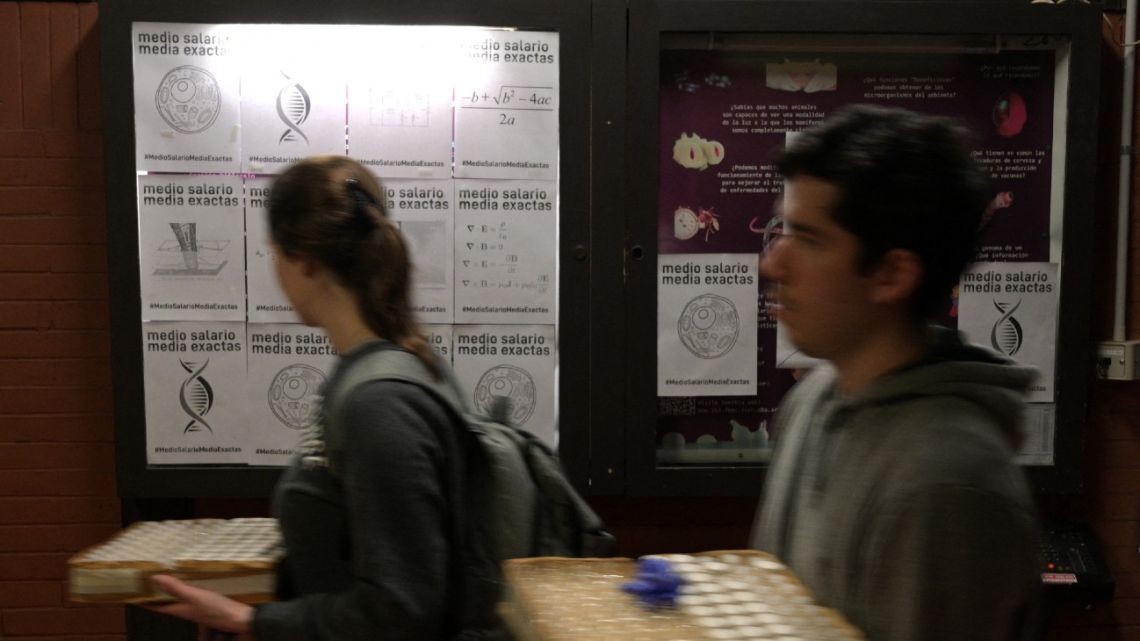 Posters reading ‘half salary, exact half’ are displayed outside the lab of the Institute of Physiology, Molecular Biology, and Neurosciences (IFIBYNE / UBA-CONICET) in Buenos Aires on September 16, 2024.