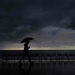 Un hombre sostiene un paraguas mientras recorre el Paseo de los Ingleses en la ciudad de Niza, en la Riviera Francesa. Foto de Valery HACHE / AFP | Foto:AFP