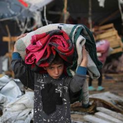 Un niño lleva objetos rescatados tras un ataque aéreo israelí la noche anterior en el campo de refugiados de Bureij, en el centro de la Franja de Gaza. Foto de Eyad BABA / AFP | Foto:AFP