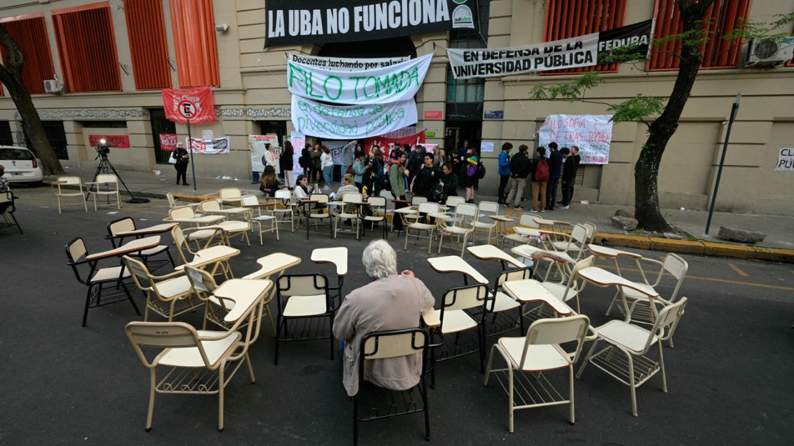 A man sits in a desk outside the Faculty of Philosophy and Letters of the University of Buenos Aires (UBA) during a protest against Argentina’s President Javier Milei's veto of a law recently passed by Congress that seeks to improve the budget of higher education institutions. 