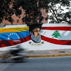 Un vehículo de motor pasa frente a un mural pintado por el Movimiento "Somos Venezuela" que representa al líder libanés de Hezbolá. Foto de Pedro MATTEY / AFP | Foto:AFP