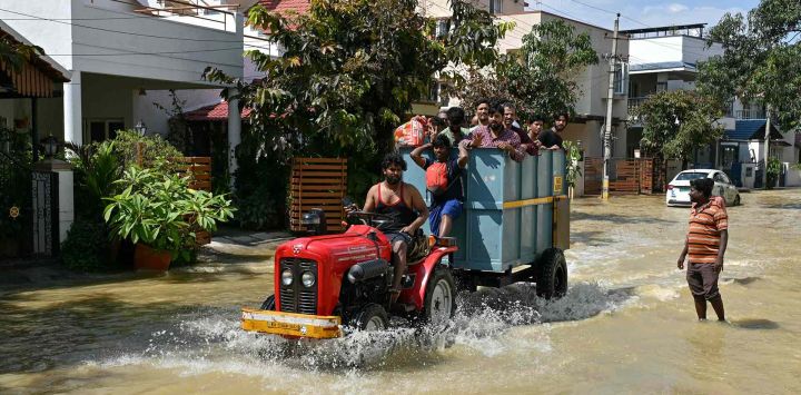 Los trabajadores se desplazan por una carretera inundada tras las fuertes lluvias en Bengaluru. Foto de Idrees MOHAMMED / AFP