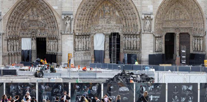 Los turistas escuchan a un guía turístico mientras los trabajadores de la construcción colocan losas en el patio delantero de la Catedral de Notre-Dame de París. Foto de Ludovic MARIN / AFP