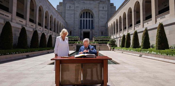 El rey Carlos III de Gran Bretaña firma un libro de visitas mientras la reina Camilla se encuentra junto a él en el Memorial de Guerra Australiano en Canberra. Foto de Brook Mitchell / AFP