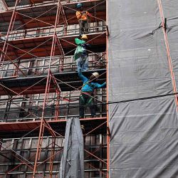Los trabajadores de la construcción en un andamio en el exterior de un centro comercial en Bangkok. Foto de Lillian SUWANRUMPHA / AFP | Foto:AFP