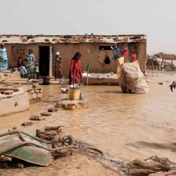 Abduli Welle y Mama Welle caminan por las aguas de la inundación frente a su casa en Odobere, Senegal. Foto de GUY PETERSON / AFP | Foto:AFP