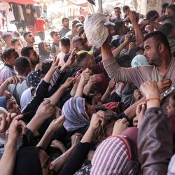 Un hombre lanza una bolsa de pan a otra persona mientras la gente se agolpa haciendo cola para comprar pan fuera de una panadería en Khan Yunis. Foto de BASHAR TALEB / AFP | Foto:AFP