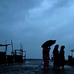 Los habitantes de la zona caminan por una playa mientras el ciclón Dana probablemente azota las costas de los estados de Bengala Occidental y Odisha. Foto de DIBYANGSHU SARKAR / AFP | Foto:AFP