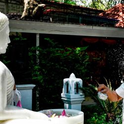 El periodista camboyano Mech Dara se vierte agua en la cabeza mientras reza frente a una estatua de Buda en una pagoda en Phnom Penh. Foto de TANG CHHIN Sothy / AFP | Foto:AFP