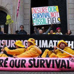 Miembros y simpatizantes del movimiento ambientalista global Extinction Rebellion, fundado en el Reino Unido, sostienen pancartas y banderas mientras organizan la navegación de un bote inflable rosa frente al Banco de Inglaterra, en el centro de Londres, durante una manifestación para pedir a la industria de seguros que deje de asegurar los combustibles fósiles. | Foto:Adrian Dennis / AFP