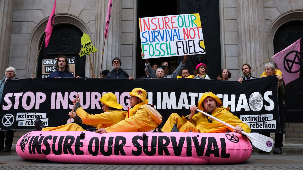 Miembros y simpatizantes del movimiento ambientalista global Extinction Rebellion, fundado en el Reino Unido, sostienen pancartas y banderas mientras organizan la navegación de un bote inflable rosa frente al Banco de Inglaterra, en el centro de Londres, durante una manifestación para pedir a la industria de seguros que deje de asegurar los combustibles fósiles. | Foto:Adrian Dennis / AFP