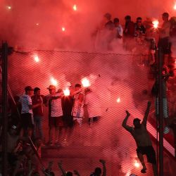 Los hinchas de Lanús encienden bengalas rojas antes del inicio del partido de vuelta de las semifinales de la Copa Sudamericana entre Lanús de Argentina y Cruzeiro de Brasil en el estadio Ciudad de Lanús en Lanús, provincia de Buenos Aires. | Foto:ALEJANDRO PAGNI / AFP
