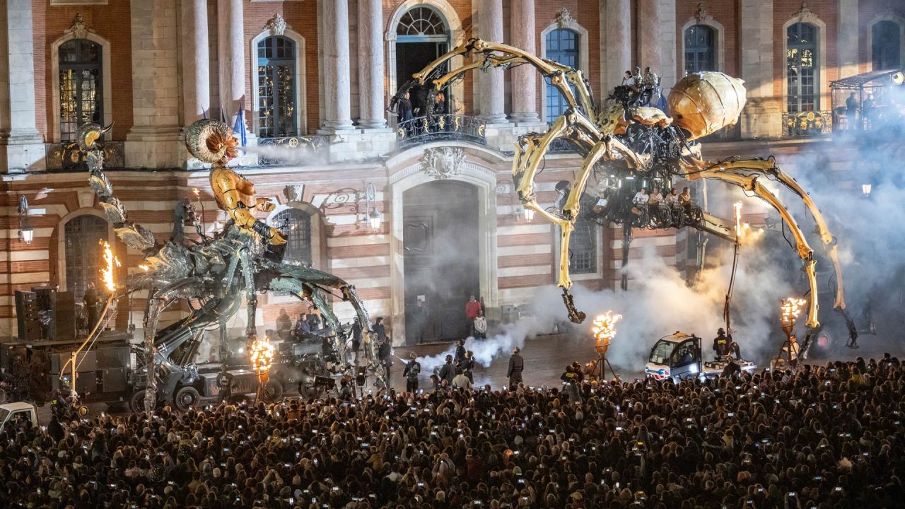 Los espectadores observan a la criatura con cabeza humana, escorpión y araña, Lilith, la guardiana de la oscuridad (izq.) y a la araña, Ariane (der.), durante el gran espectáculo callejero "El guardián del templo opus II: El portal de las tinieblas" de la compañía francesa La Machine, en Toulouse, suroeste de Francia. | Foto:LIONEL BONAVENTURE / AFP