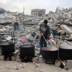 Un hombre prepara comida para distribuirla entre los palestinos desplazados frente a un edificio derribado en la ciudad de Gaza, en medio de la guerra en curso entre Israel y militantes de Hamás. | Foto:OMAR AL-QATTAA / AFP