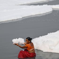 Una mujer que sostiene espuma tóxica posa para una fotografía en las orillas del contaminado río Yamuna en Nueva Delhi, India. | Foto:Sajjad Hussain / AFP
