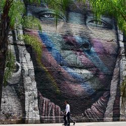 La gente camina junto a un grafiti realizado por el artista brasileño Kobra en la zona portuaria de Río de Janeiro, Brasil. | Foto:MAURO PIMENTEL / AFP