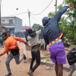 Los manifestantes lanzan piedras mientras se enfrentan a la policía antidisturbios de Mozambique en Maputo. Las tensiones aumentaban en Maputo, cuando la policía lanzó gases lacrimógenos para dispersar a los manifestantes reunidos después de que el principal líder de la oposición llamara a manifestarse por los resultados de las elecciones. | Foto:ALFREDO ZUNIGA / AFP