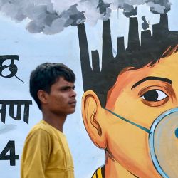Un hombre pasa junto a un mural pintado para crear conciencia sobre el problema del calentamiento global y la contaminación en Varanasi, India. | Foto:NIHARIKA KULKARNI / AFP