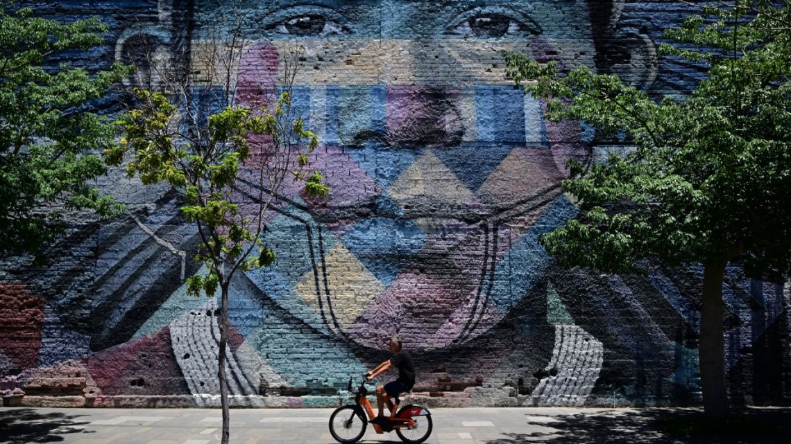 A man on a bicycle rides past grafitti made by Brazilian artist Kobra at the port zone of Rio de Janeiro, Brazil, on November 6, 2024. The G20 Social Summit will take place at the port zone of Rio de Janeiro between November 14 and 16, 2024, on the eve of the G20 Leaders' Summit. 