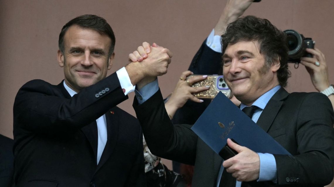 France's President Emmanuel Macron and Argentina's President Javier Milei hold hands on the balcony of the Casa Rosada after a meeting in Buenos Aires on November 17, 2024.