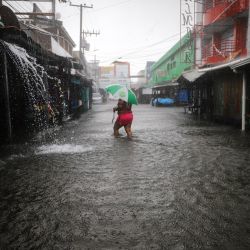 Una mujer camina por una calle inundada durante el paso de la tormenta tropical Sara en La Ceiba, Honduras. | Foto:ESAU OCAMPO / AFP
