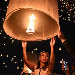 La gente enciende y suelta linternas de papel durante las celebraciones del festival Yi Peng en la ciudad de Chiang Mai, en el norte de Tailandia. | Foto:MANAN VATSYAYANA / AFP